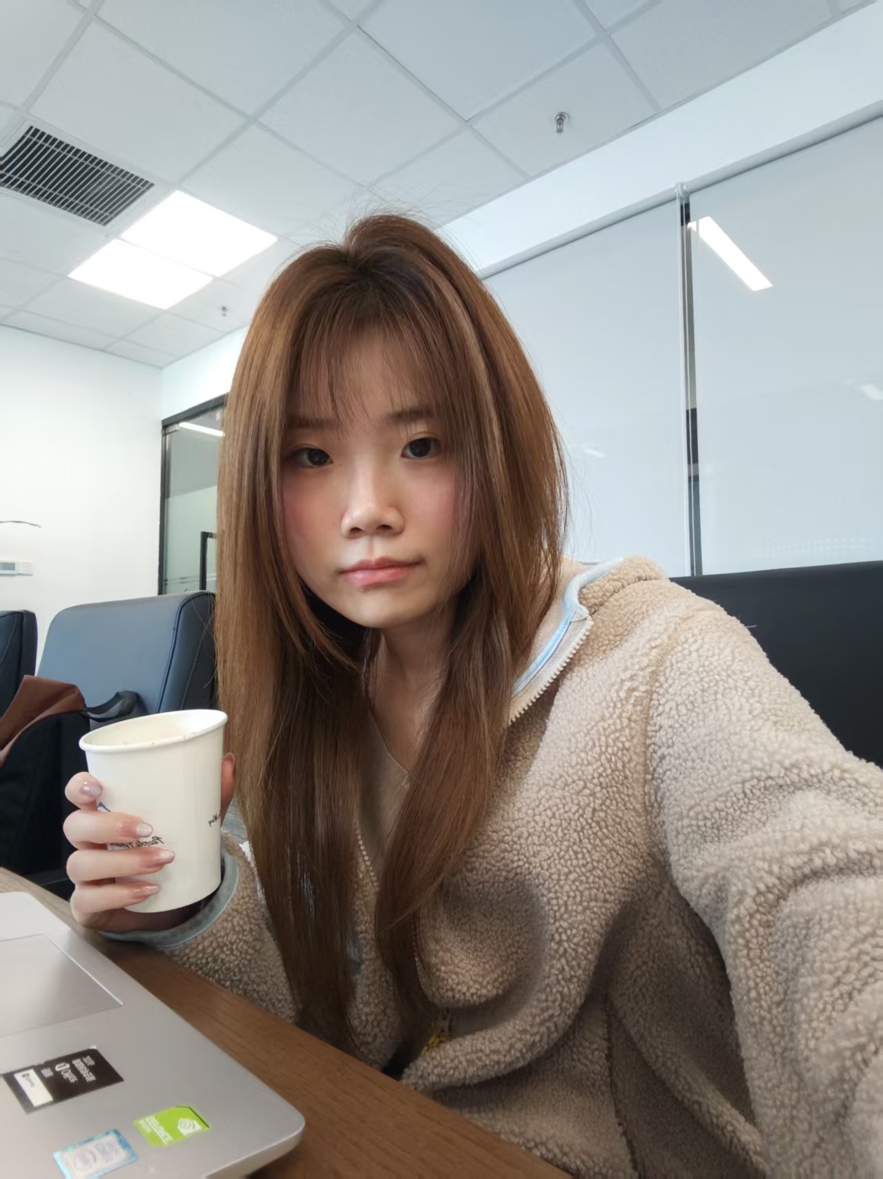 刘奕瑾在工作场景中手持咖啡的生活照